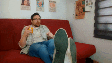 a man is sitting on a couch with his feet up and a wanted poster on the wall behind him