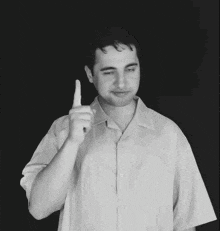 a man in a white shirt holds up his finger