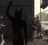 a silhouette of a person with a cat 's head raising their hand in the air