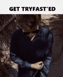 a man in a black shirt is standing in front of a fence with the words get tryfasted above him