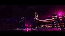 a group of people are singing and playing guitars on stage