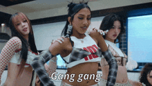 a group of women are dancing and one of them is wearing a crop top that says gang gang on it