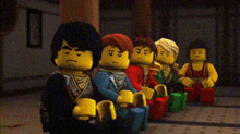 a group of lego figures are sitting in a row and one of them has the word ninja written on his head .