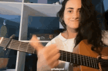 a woman playing a guitar with the words gifsdayrol on the bottom right