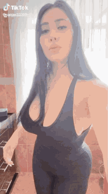 a woman in a black tank top and leggings is taking a selfie in a bathroom .