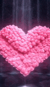 a heart made of pink flowers is being poured into a glass .