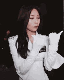 a woman in a white jacket and gloves is giving a thumbs up sign .