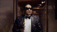 a man in a tuxedo and bow tie is wearing sunglasses and making a funny face