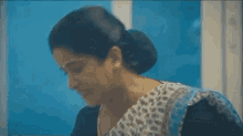 a woman is sitting in front of a window with her hand on her head .