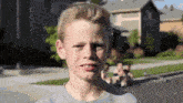 a young boy in a grey shirt is making a face