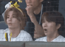 two young men are sitting in a stadium watching a baseball game .