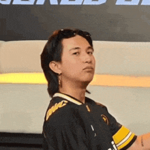 a young man wearing a black and yellow shirt and sunglasses is standing in front of a couch .