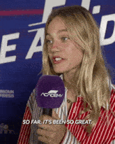 a woman holding a microphone with a purple academy logo on it