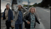 three men are walking down a street and one has a beard
