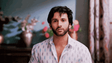 a man with a beard and a white shirt is looking at the camera