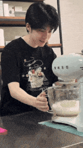 a man in a black shirt is using a smeg mixer to mix something