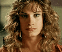 a close up of a woman with curly hair and earrings .