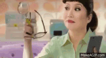 a woman is holding a glass of wine and a cell phone in her hand .