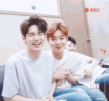 a group of young men are sitting on a couch laughing and holding hands .