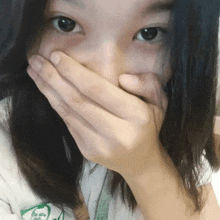 a girl covering her mouth with her hand and wearing a shirt that has a picture of a man