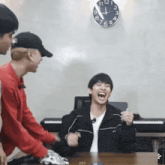 a man is laughing in front of a clock that shows the time as 11:12