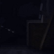 a girl with long hair is peeking out of a dark room .