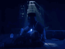 a man is sitting in a dark room with a blue light shining on him