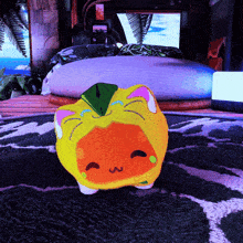 a yellow and orange stuffed animal is sitting on a rug