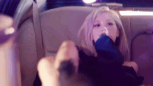 a woman is sitting in the back seat of a car with a purple background .
