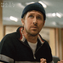 a man wearing a beanie and a sweater with project hail mary written on the bottom right