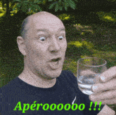 a man is holding a glass of water with the words apéroooooo written on the bottom