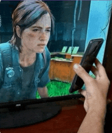 a person is holding a phone in front of an aoc television