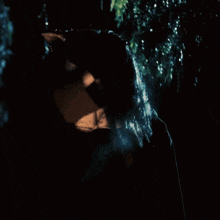a woman in a black jacket is standing in a dark room .