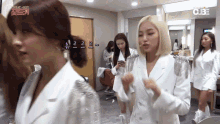 a group of women are standing in a dressing room and one of them is looking at her phone .