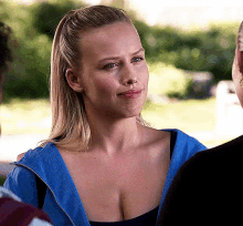 a woman wearing a blue hoodie and a black tank top is talking to another woman