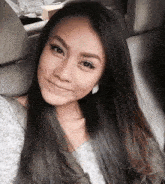 a woman with long black hair is smiling while sitting in a car seat