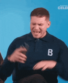 a man in a blue shirt is dancing in front of a blue background with the word celeb on it .