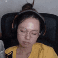 a woman wearing headphones and glasses is sleeping in a chair .