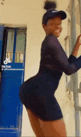 a woman in a black dress is standing in front of a blue door with tiktok written on the bottom