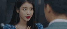 a woman in a blue dress with red lipstick is looking at a man .