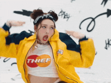 a woman wearing a yellow jacket and a white crop top that says thief