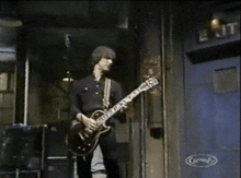 a man playing a guitar in front of a sign that says " comedy "