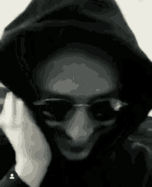 a black and white photo of a person wearing sunglasses and a hood .