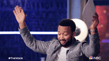 a man with his arms in the air is on a nbc show called the voice