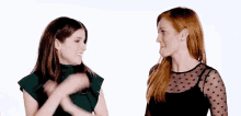 two women are standing next to each other on a white background . one of the women has red hair and the other has brown hair .