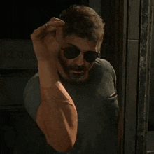 a man wearing sunglasses and a beard is waving his hand .