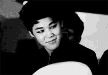 a black and white photo of a young man smiling in a room .