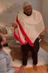 a man wearing a white cape with a red stripe is pointing at someone