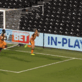 a soccer player runs towards a goal in front of an in-play sign