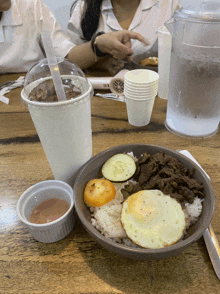 a bowl of food on a table next to a cup of coffee